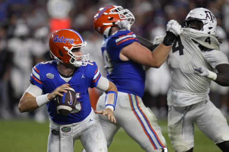 Florida quarterback Graham Mertz, left, looks for a receiver as offensive lineman Austin Barber, center, blocks Texas A&M defensive lineman Shemar Stewart (4) during the second half of an NCAA college football game, Saturday, Sept. 14, 2024, in Gainesville, Fla. (AP Photo/John Raoux)