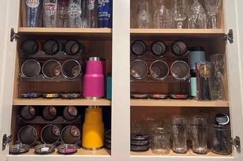 Organized kitchen cupboard holding various tumblers and lids