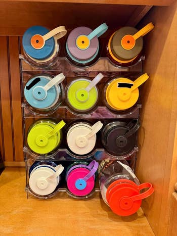 Image shows a display of reusable water bottles organized neatly in a clear rack