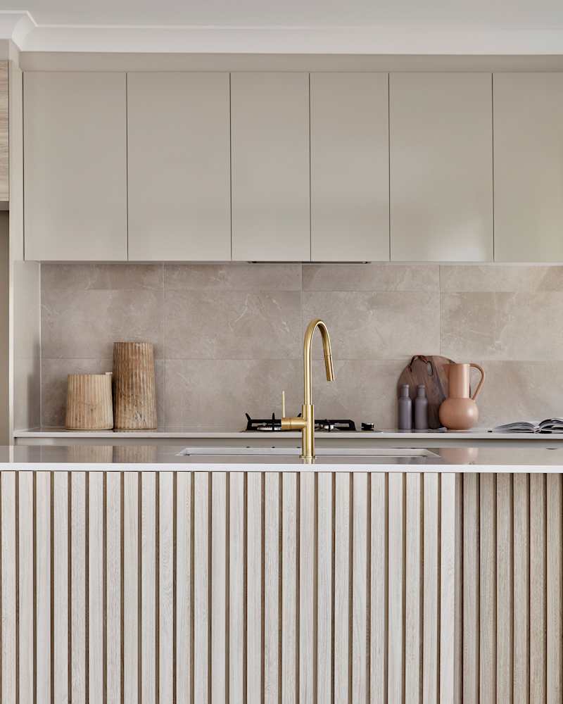 Detail of a contemporary Scandi style kitchen with fluted cabinetry detail in light oak timber.