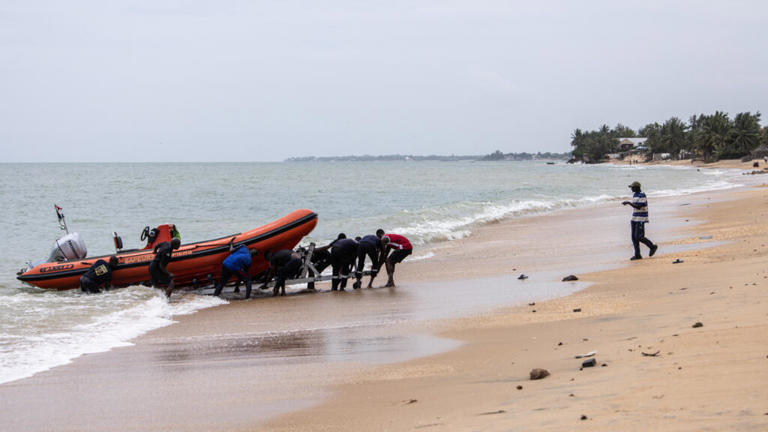 Des membres d'une équipe de recherche et de sauvetage tirant un bateau vers le rivage à la fin d'une recherche pour retrouver des survivants et récupérer les morts après le naufrage d'une pirogue transportant plus de 150 migrants, à Mbour le 9 septembre 2024.