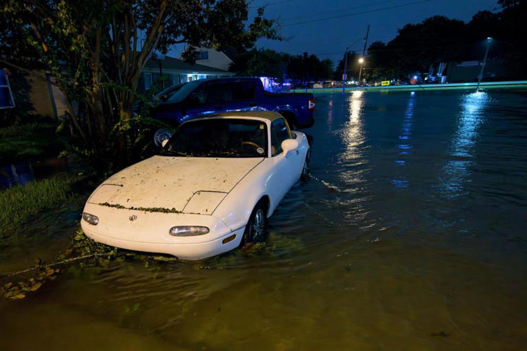 A car is submerged to its wheel well on Neyrey Dr. as water overflows the nearby W. Napoleon Ave drainage canal after a deluge of rain from Hurricane Francine in Metairie, La., in Jefferson Parish, Sept. 11, 2024.