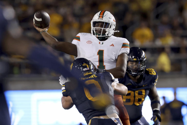 Miami quarterback Cam Ward (1) passes against California linebacker Cade Uluave (0) during the first half of an NCAA college football game in Berkeley, Calif., Saturday, Oct. 5, 2024. (AP Photo/Jed Jacobsohn)