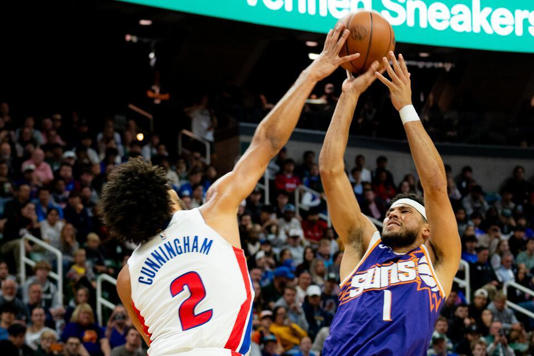 Detroit guard Cade Cunningham (2) blocks Phoenix guard Devin Booker (1) during a NBA preseason game between the Phoenix Suns and Detroit Pistons at the Breslin Center in East Lansing, Michigan, on Tuesday, Oct. 8, 2024.