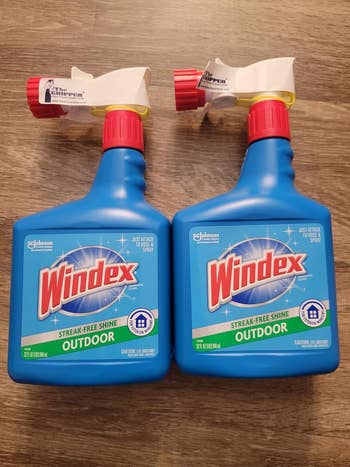 Two bottles of Windex Outdoor spray cleaner with streak-free shine formula on a wooden surface