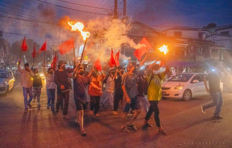 Pro-democracy protesters hold torches and flags during a flash mob rally to protest against Myanmar’s military government in Yangon