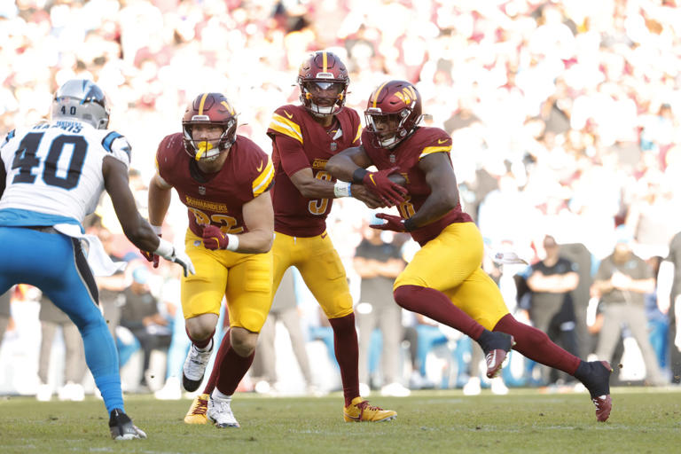 Washington Commanders quarterback Jayden Daniels (5) hands the ball to Commanders running back Brian Robinson Jr. (8) during the first quarter against the Carolina Panthers at Northwest Stadium. © Amber Searls-Imagn Images