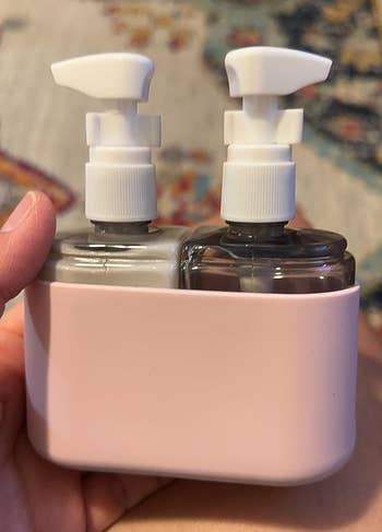 A small pink holder with two travel-sized bottles with pump dispensers tucked inside
