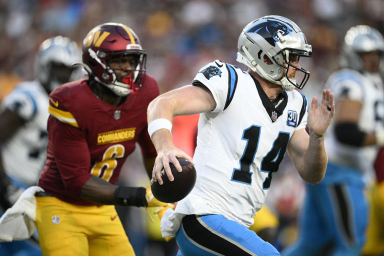 Carolina Panthers quarterback Andy Dalton (14) runs from Washington Commanders linebacker Dante Fowler Jr. (6) during the second half of an NFL football game, Sunday, Oct. 20, 2024, in Landover, Md. (AP Photo/Nick Wass)