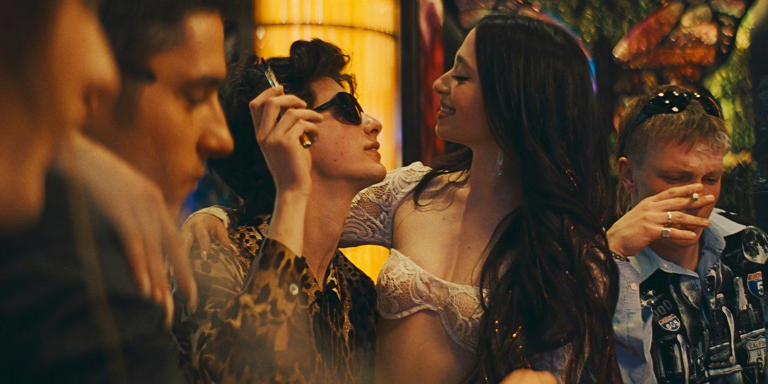 Ani sitting in Ivan's lap at a card table in Las Vegas surrounded by other men in Anora