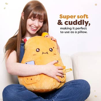 Model smiling while hugging a large plush toy with a cute face. Text reads: