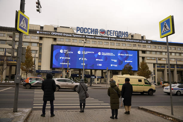 Pedestrians stand at the crossing in front the Rossiya Segodnya International Media Group building with a running news line about the U.S. elections, top, in Moscow, Russia, Wednesday, Nov. 6, 2024. (AP Photo/Pavel Bednyakov)