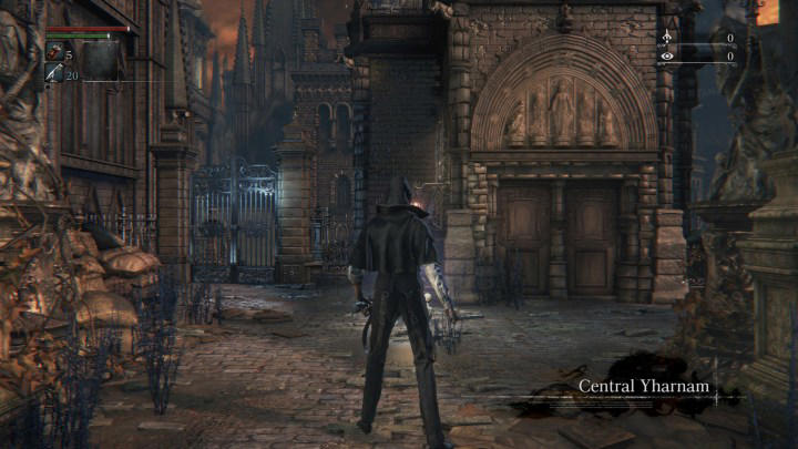 The main character of Bloodborne stands in front of a building.