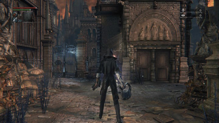 The main character of Bloodborne stands in front of a building.