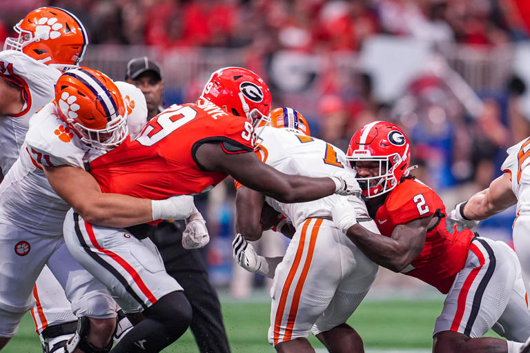 Aug 31, 2024; Atlanta, Georgia, USA; Clemson Tigers running back Phil Mafah (7) is tackled by Georgia Bulldogs defensive lineman Joseph Jonah-Ajonye (99) and linebacker Smael Mondon Jr. (2) during the first half at Mercedes-Benz Stadium. Mandatory Credit: Dale Zanine-USA TODAY Sports