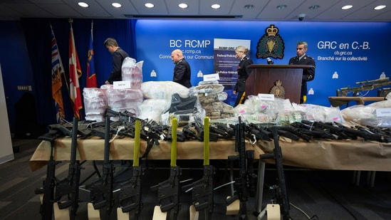 Firearms and illicit drugs seized last week are displayed as Royal Canadian Mounted Police Chief Supt. Stephen Lee, back from left, Asst. Commissioner David Teboul, Insp. Jillian Wellard and Cpl. Arash Seyed leave after a news conference at RCMP headquarters, in Surrey, British Columbia,