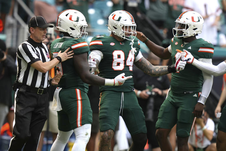 Miami tight end Cam McCormick (84) celebrates with tight end Elija Lofton (9) and quarterback Cam Ward, right, after scoring a touchdown during the first half of an NCAA college football game, Saturday, Nov. 2, 2024, in Miami Gardens, Fla. (AP Photo/Lynne Sladky)