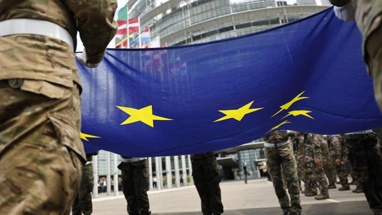 Militares seguram a bandeira da União Europeia enquanto participam numa cerimónia de hastear da bandeira