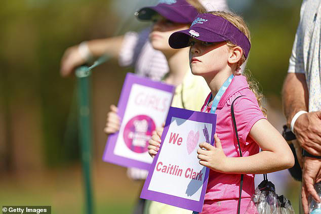 Two young girls held posters that read, 'We heart Caitlin Clark,' from behind the ropes