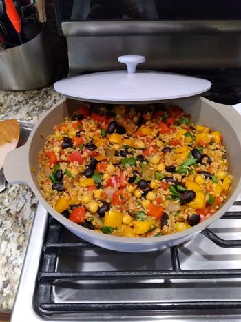 A pot of mixed vegetable and grain salad with beans, corn, and diced vegetables on a kitchen stovetop