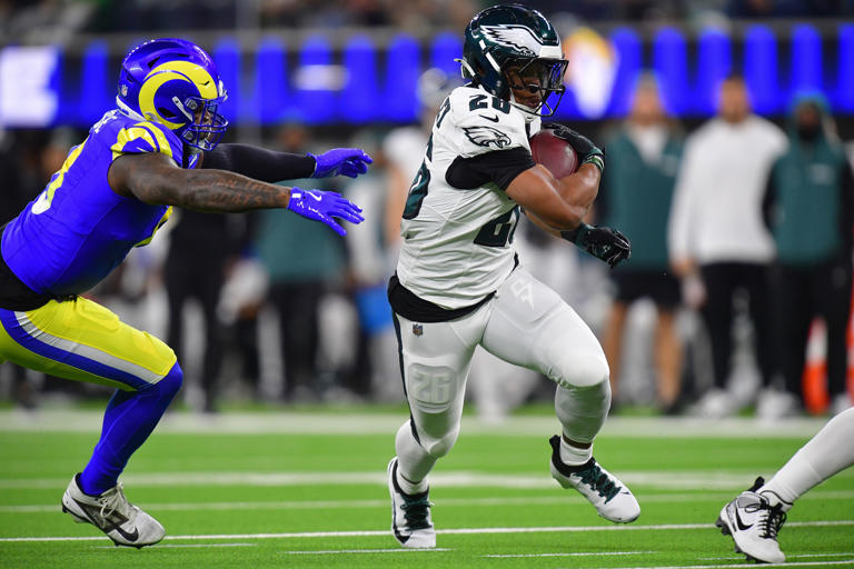 Nov 24, 2024; Inglewood, California, USA; Philadelphia Eagles running back Saquon Barkley (26) runs the ball ahead of Los Angeles Rams safety Quentin Lake (37) during the first half at SoFi Stadium. Mandatory Credit: Gary A. Vasquez-Imagn Images