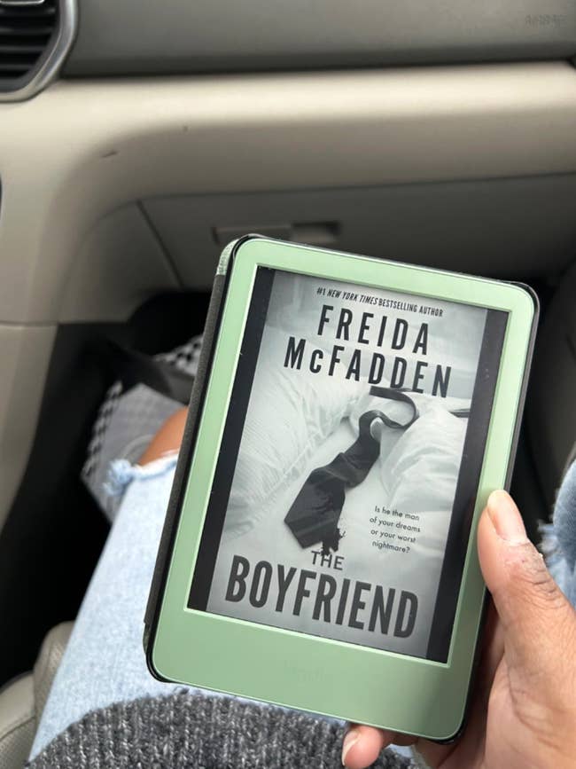 Person holding an e-reader displaying the book cover for