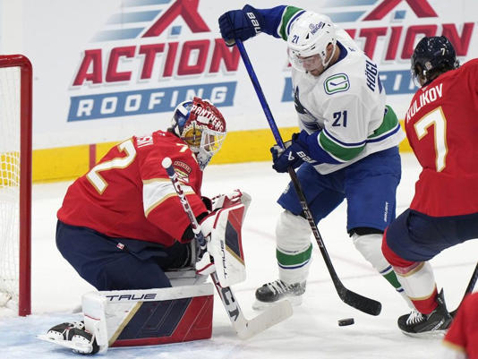  Vancouver Canucks left wing Nils Hoglander (21) attempts a shot at Florida Panthers goaltender Sergei Bobrovsky (72) and defenseman Dmitry Kulikov (7) during the second period of an NHL hockey game, Thursday, Oct. 17, 2024, in Sunrise, Fla.