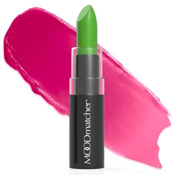 Green lipstick in a Moodmatcher tube with a pink smear behind it, illustrating its color-changing feature for personalized shopping