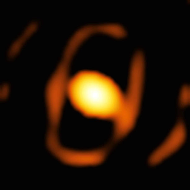 De betreffende close-upfoto van de ster WOH G64, gemaakt met het GRAVITY-instrument op de VLTI van de ESO. Het is de eerste close-upfoto van een ster buiten onze eigen Melkweg. De ster bevindt zich in de Grote Magelhaanse Wolk, op meer dan 160.000 lichtjaar afstand. Het heldere ovaal in het midden van de afbeelding is een stoffige cocon die de ster omhult. Een zwakker ellipsvormig ring rondom de cocon zou de binnenrand van een stoffige torus (een ringvormige structuur van stof en gas die de ster omringt) kunnen zijn. Afbeelding: ESO/K. Ohnaka et al.