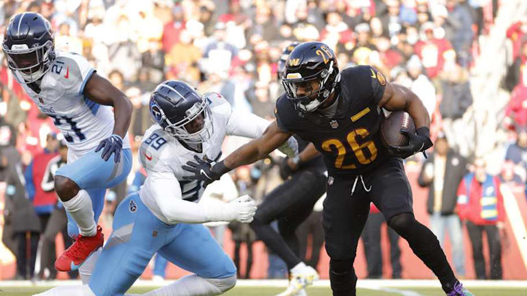 Dec 1, 2024; Landover, Maryland, USA; Washington Commanders running back Jeremy McNichols (26) carries the ball as Tennessee Titans linebacker Ali Gaye (99) defends during the first half at Northwest Stadium. Mandatory Credit: Amber Searls-Imagn Images | Amber Searls-Imagn Images