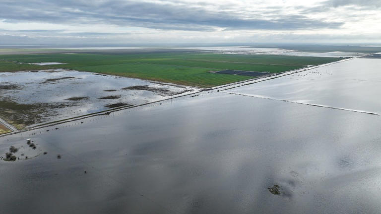Flooding scenes in San Joaquin Valley, California, show a large body of water, presumably Tulare Lake’s resurgence, with a distant field and residents dealing with the situation. Los Angeles Times via Getty Images