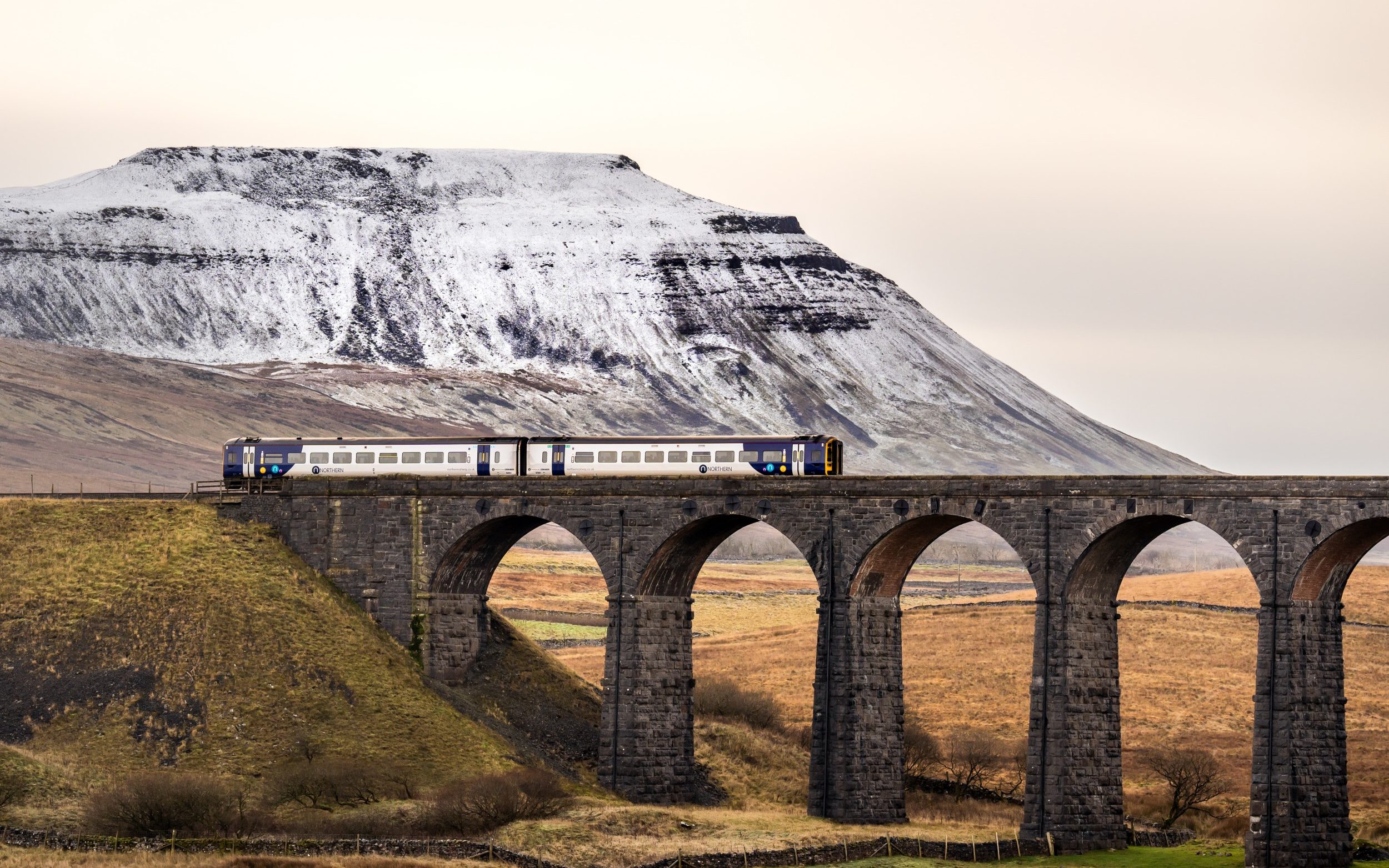 Ribblehead Viaduct passes by the snow-capped mountain of Ingleborough in the Yorkshire Dales