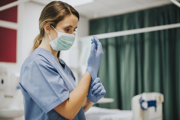 Female nurse with a mask putting on gloves