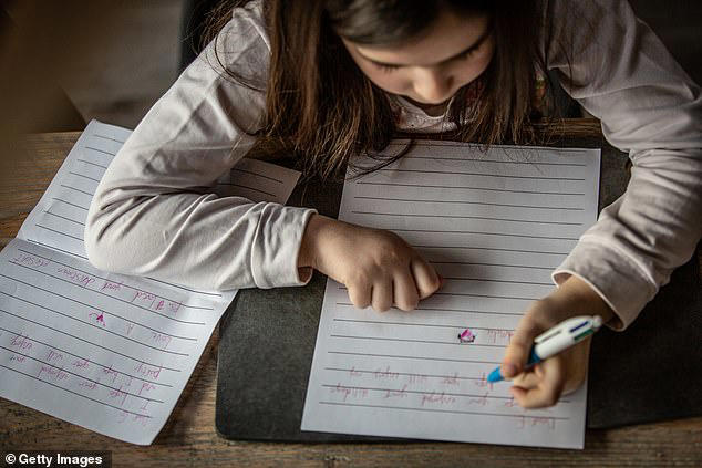 A young girl writing (stock image). Pupils' handwriting is so poor that it can be ‘impossible to award a fair mark’ to their work, chief examiners warn