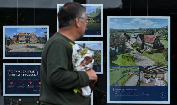 A man walks past an estate agent's window