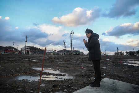 大規模火災で焼けた建物の解体が進む石川県輪島市の観光名所「朝市通り」近くに住む二俣大輔さん（４８）。犠牲者に手を合わせると、「子どもの頃によく遊んだ思い出の場所。地震が先月だったみたいに、あっという間に過ぎた１年だった」と振り返った＝３１日午後