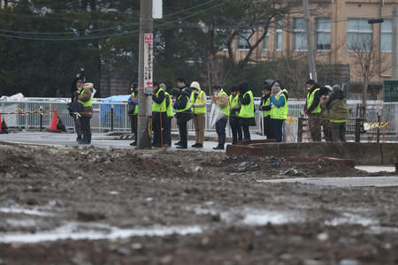 大規模火災が起きた石川県輪島市の観光名所「朝市通り」付近では被災建物の解体が進み、大みそかには手を合わせる人の姿が見られた＝３１日午後