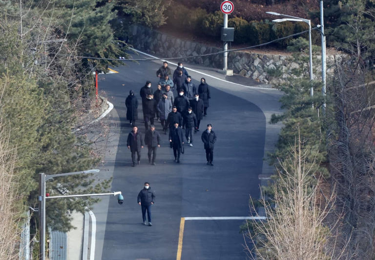 Investigators walk from the presidential residence in Seoul after calling off their attempt to arrest the impeached president.