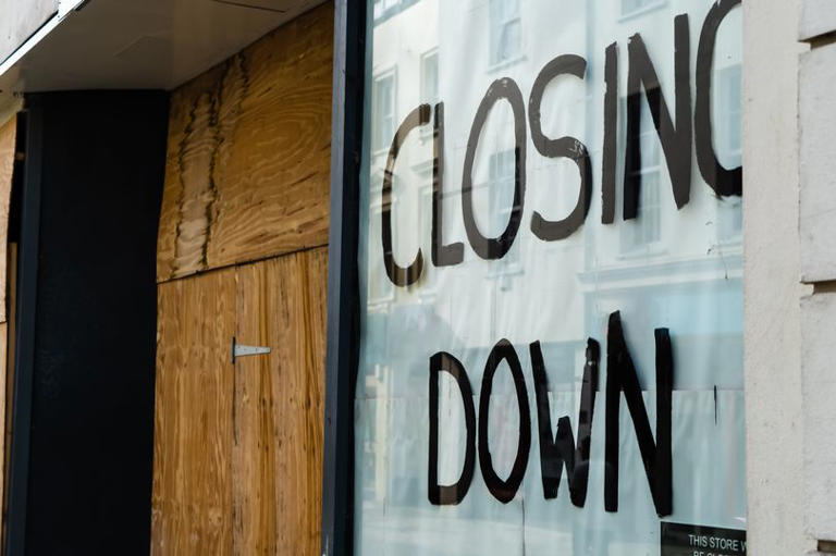 Closing down sign in a boarded-up shop window