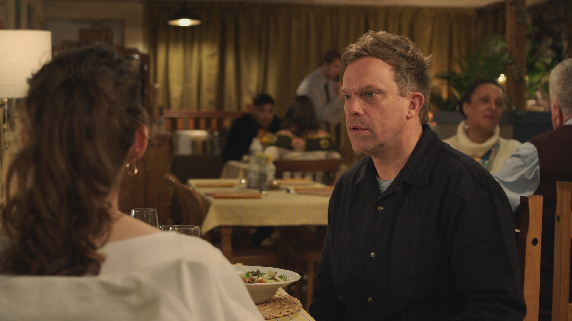 Dylan Keogh is surprised and apologetic over dinner when Jodie reacts negatively to his revelation about Max. (Image credit: BBC Studios)