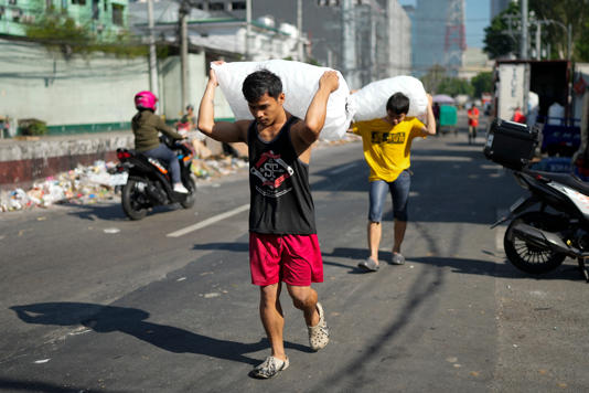 Men deliver sacks of ice cubes as hot temperatures persist in Quezon city, Philippines (AP)