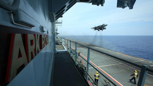 A Harrier jet hovering over an aircraft carrier