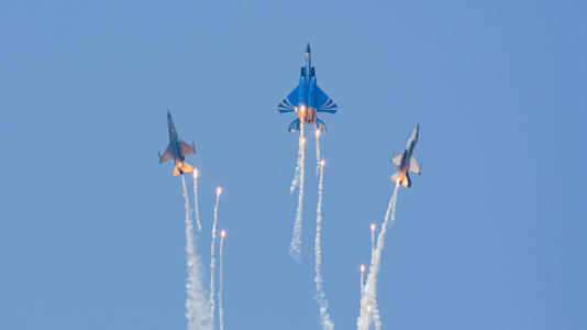 three fighter jets releasing flares in a flight display