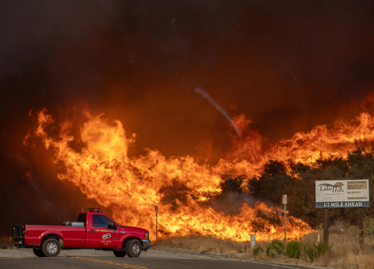 A firefighter truck backs up from flames of smoke from the new Hughes Fire at the Lake Hughes Road in Castaic, a northwestern neighborhood of Los Angeles, California (AFP via Getty Images)