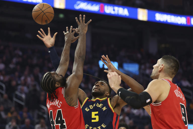 Golden State Warriors forward Kevon Looney (5) shoots against Chicago Bulls forward Patrick Williams (44) center Nikola Vucevic (9) during the first half of an NBA basketball game in San Francisco, Thursday, Jan. 23, 2025. (AP Photo/Jed Jacobsohn)