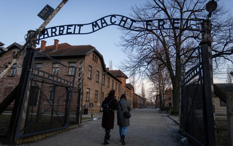 Two women pass by the gate at the Memorial and Museum at Auschwitz-Birkenau (AFP via Getty Images)