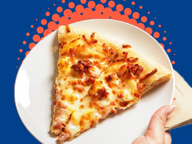 Two slices of pizza with bacon, egg and cheese on top on a plate being held in a hand with a paper napkin.