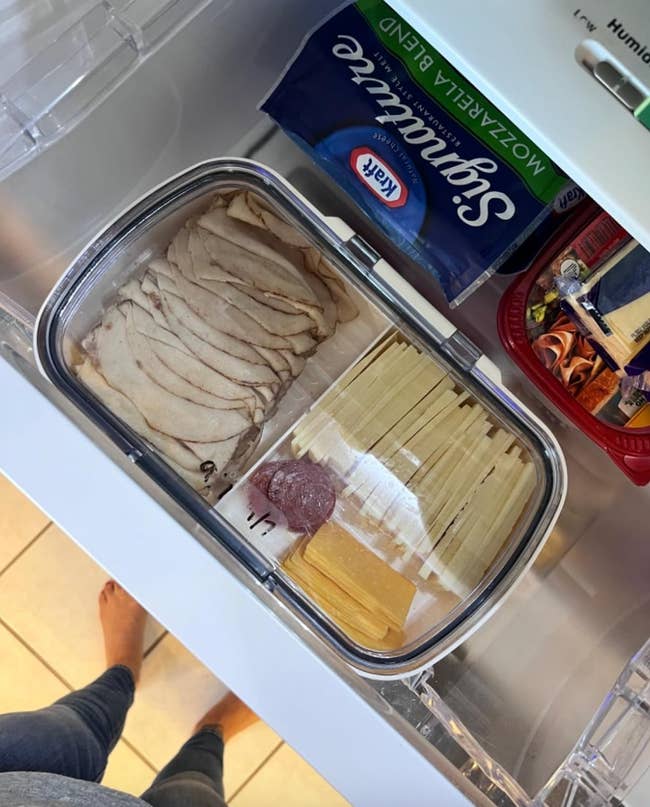 Refrigerator drawer with sliced deli meats, cheese, and pasta sheets, viewed from above