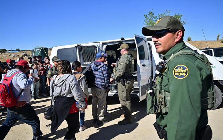 Customs and Border Patrol agents load migrants into a vehicle after groups of migrants walked into the US from Mexico at Jacumba Hot Springs, California, on June 5, 2024.