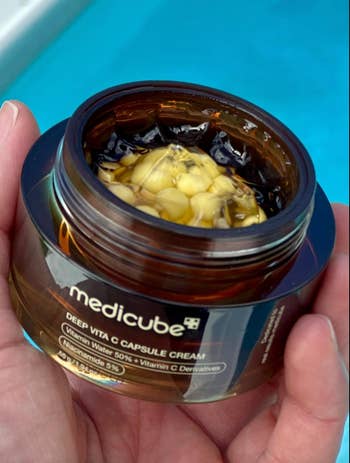 Close-up of an open jar of Medicube Deep Vita C Capsule Cream, showing its textured contents